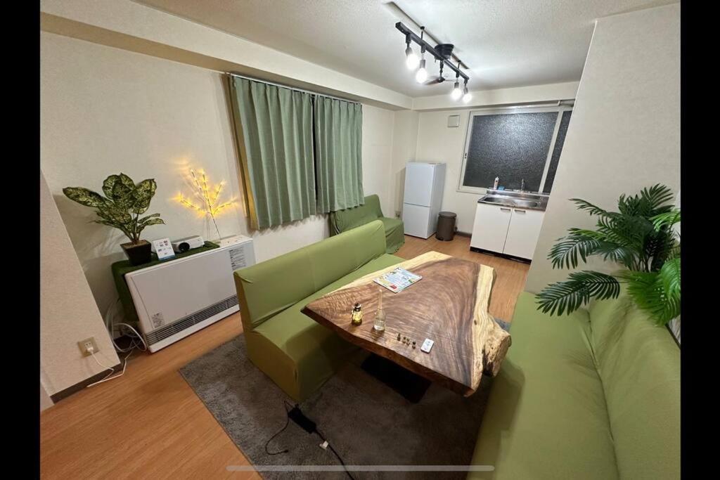 un salon avec un canapé vert et une table dans l'établissement Monster lodge 札幌, à Sapporo