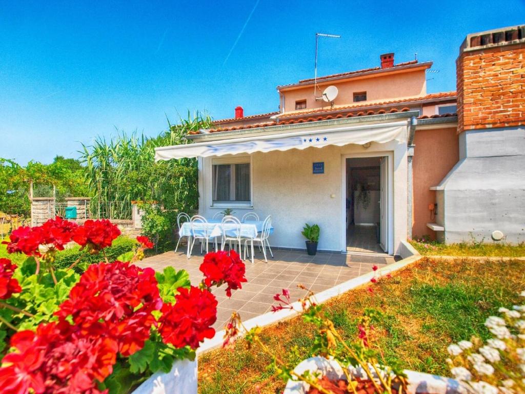 una casa con flores rojas y sillas en un patio en Ferienwohnung für 6 Personen ca 75 qm in Fažana, Istrien Istrische Riviera - b54751, en Fažana