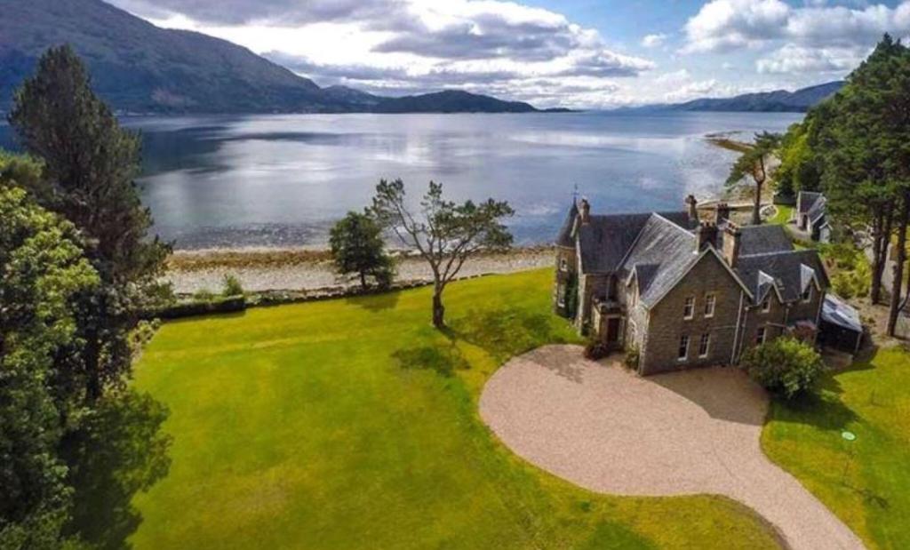 an aerial view of a house on the shore of a lake at Ardrhu House Fort William - Serviced Luxury Scots Baronial Country House in Fort William