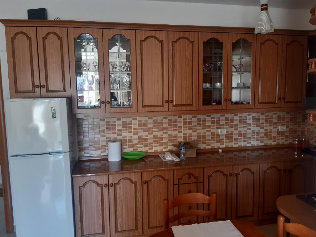 a kitchen with wooden cabinets and a white refrigerator at Emily House in Fier