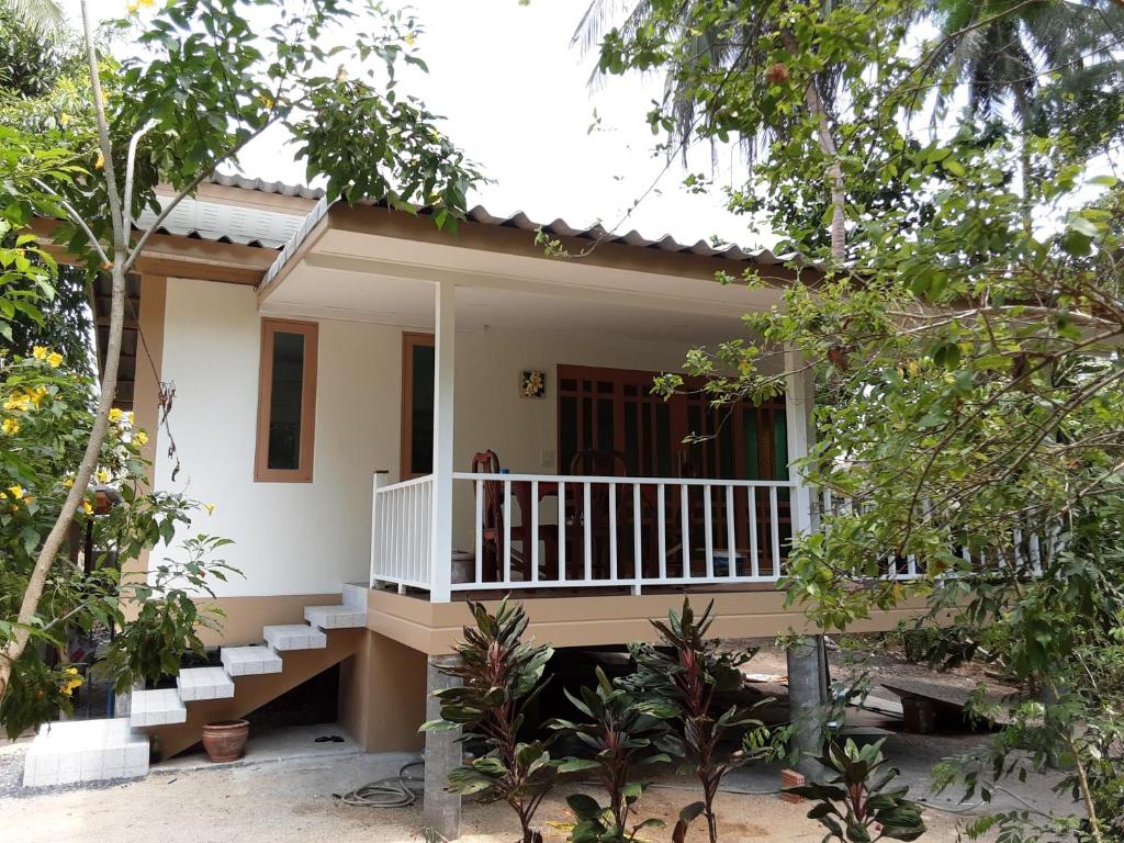 a small house with a balcony in a forest at Baan Moonchan House in Chaloklum