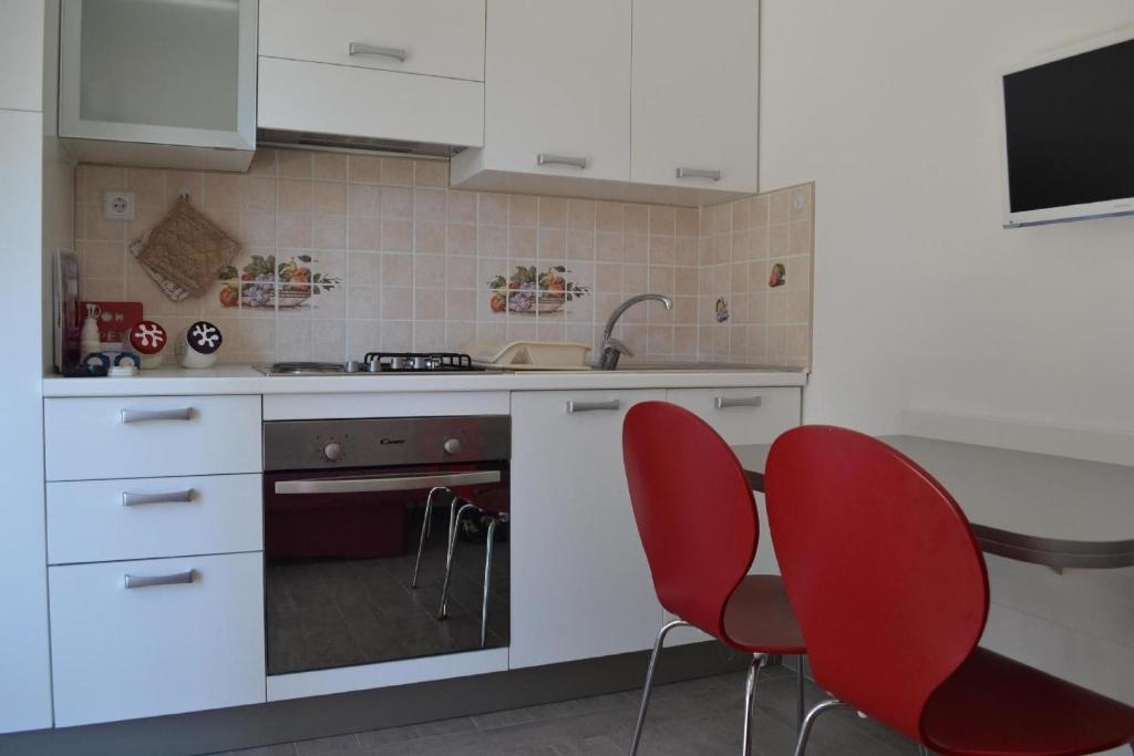 uma cozinha com armários brancos e cadeiras vermelhas em Ferienwohnung für 4 Personen ca 45 qm in Srima, Dalmatien Norddalmatien - b60464 em Srima