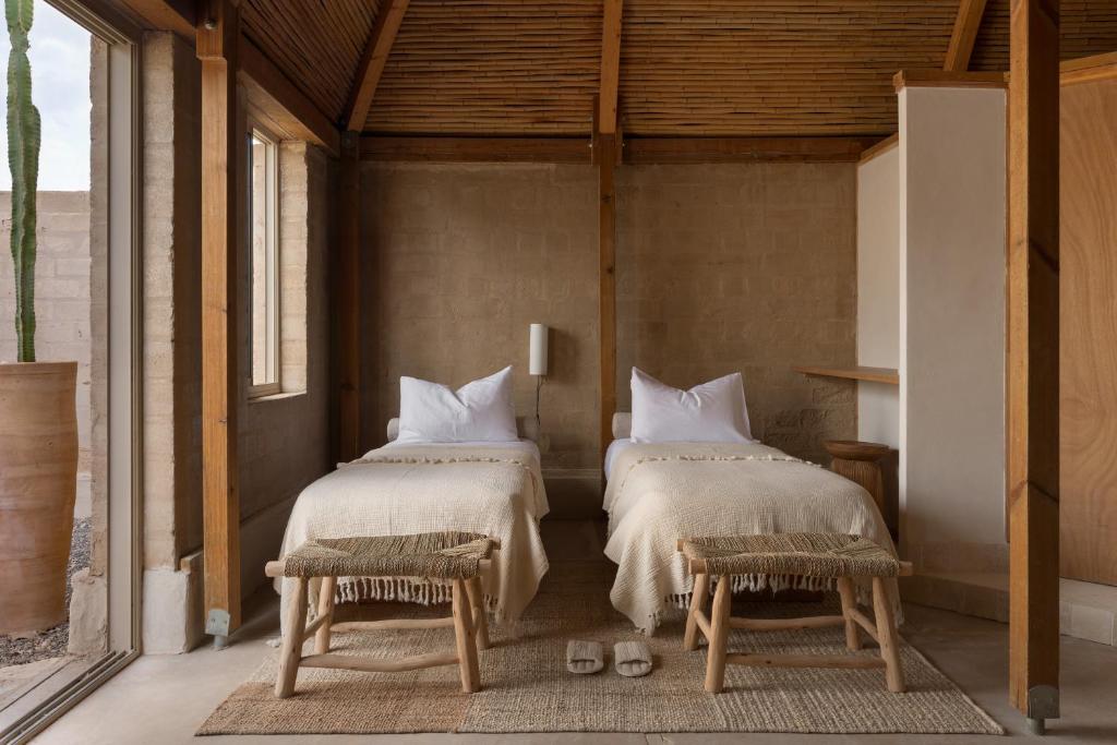 a bedroom with two beds and two chairs at Moa Living in Ẕofar