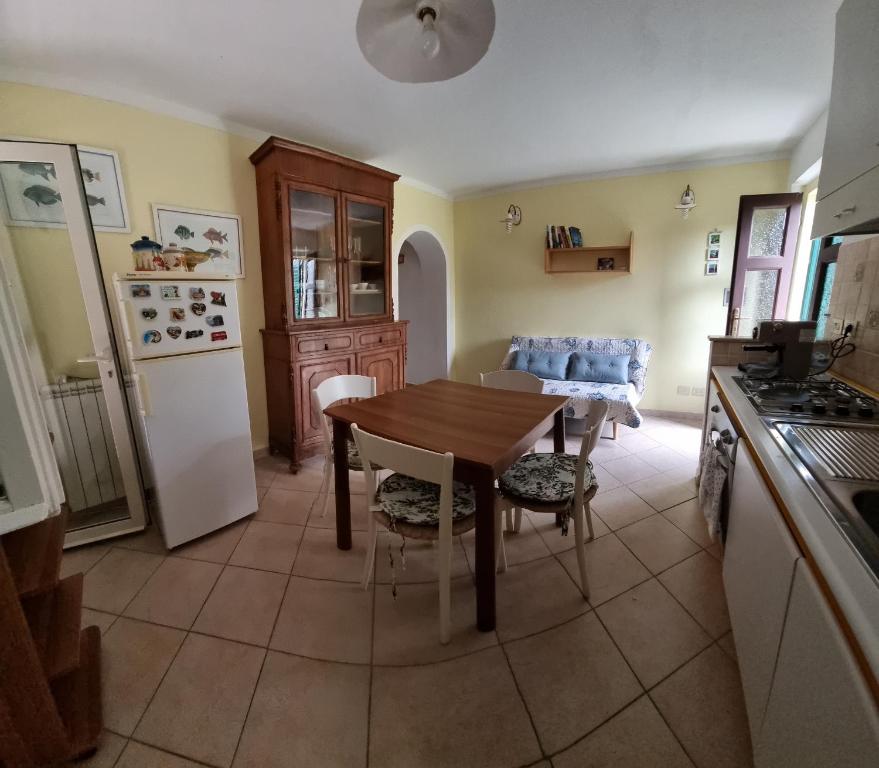a kitchen with a wooden table and a white refrigerator at CASA ORCHIDEA in Portoferraio