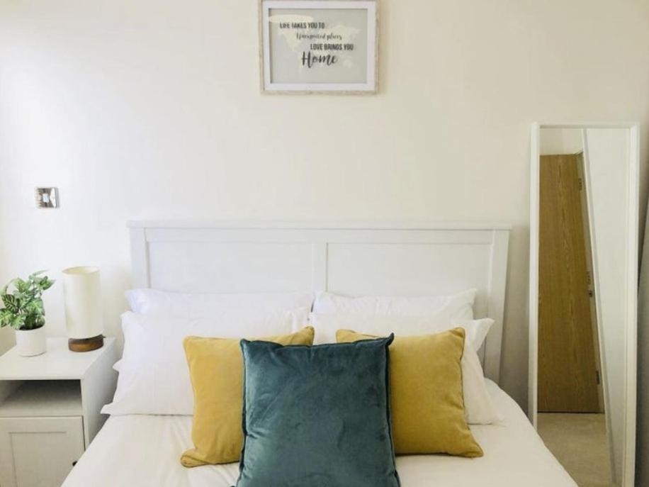 a bedroom with a white bed with yellow pillows at Charming double-bedroom in London Flat in London