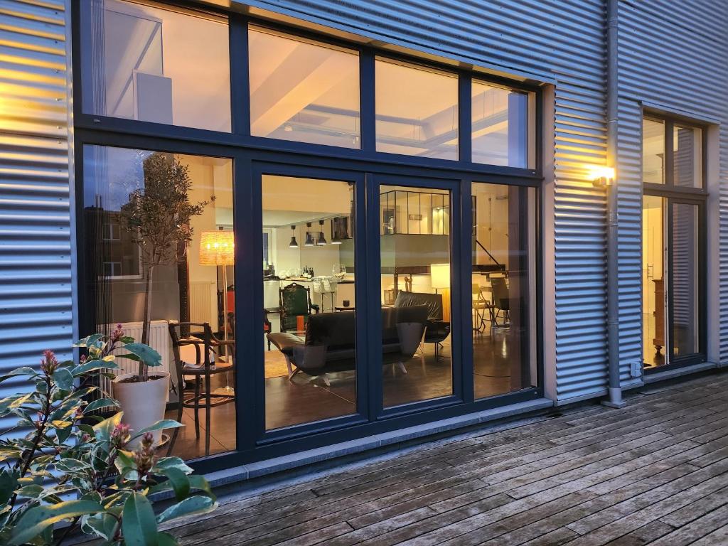 een woonkamer met grote glazen ramen op een huis bij Liège : superbe loft de caractère à 10' du centre in Luik
