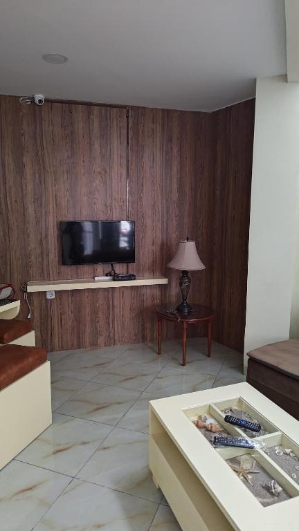 a living room with a tv on a wooden wall at D'Coz RedLiving Star Semarang in Jomblang