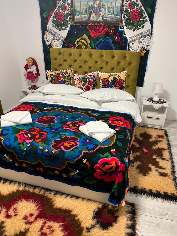 een slaapkamer met een bed met een kleurrijk dekbed bij Vila PauDeea in Moisei