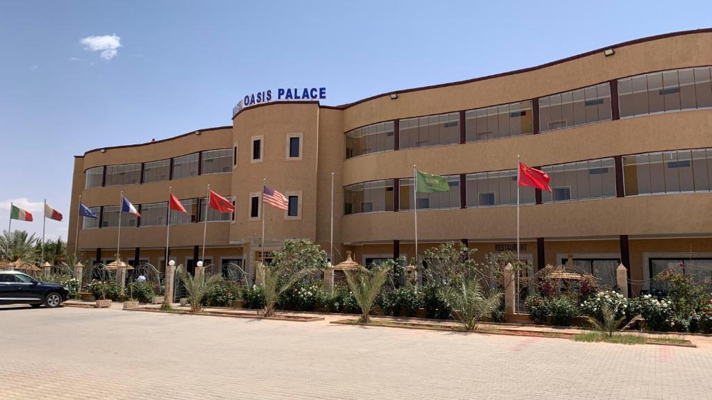 un edificio con un montón de banderas delante de él en Hotel Oasis Palace, en Er Rachidia
