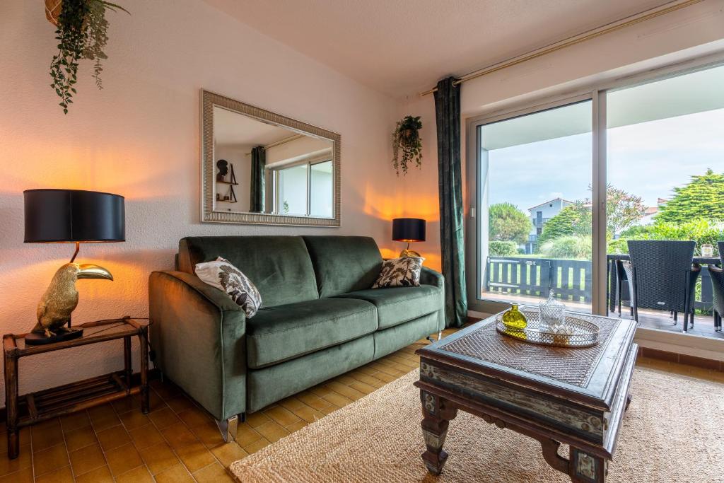 a living room with a green couch and a table at Studio plage de Capbreton avec terrasse in Capbreton