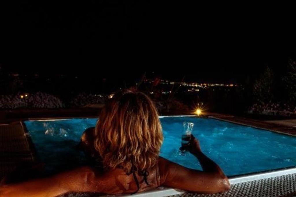 Eine Frau, die im Pool mit einem Glas Wein sitzt. in der Unterkunft Cyclopes House Amazing view and Private Mini Spa in Aci Catena