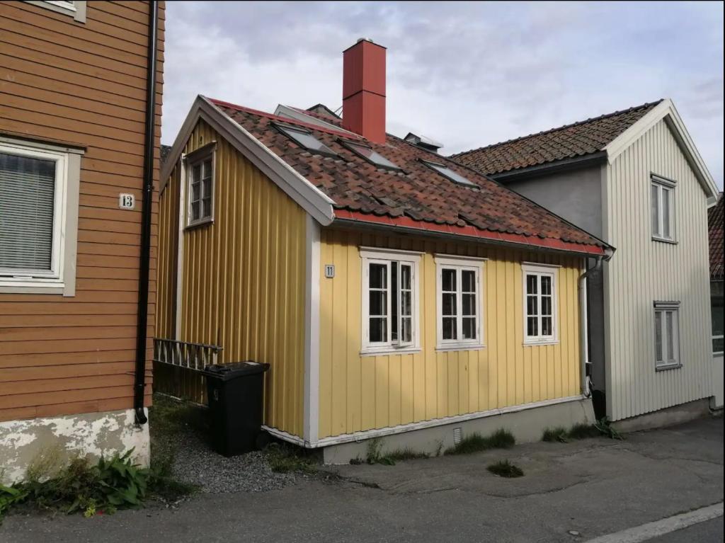 um pequeno edifício amarelo ao lado de uma casa em Sjarmerende historisk leilighet midt i Tromsø em Tromsø