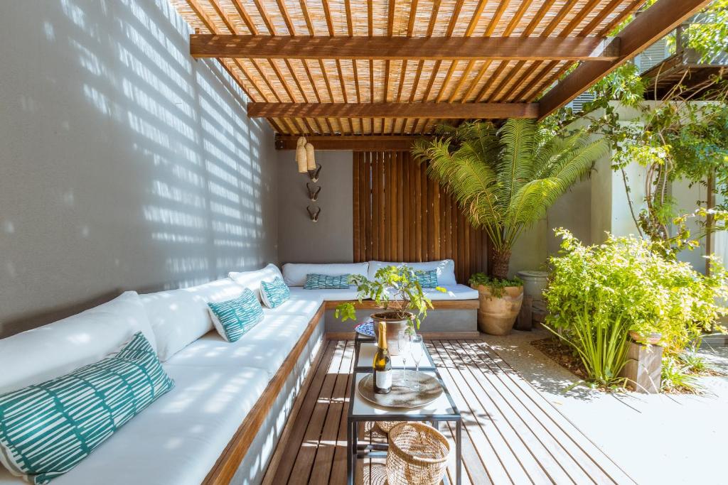 un patio con un sofá blanco y una pérgola de madera en Cape Standard Guest House en Ciudad del Cabo