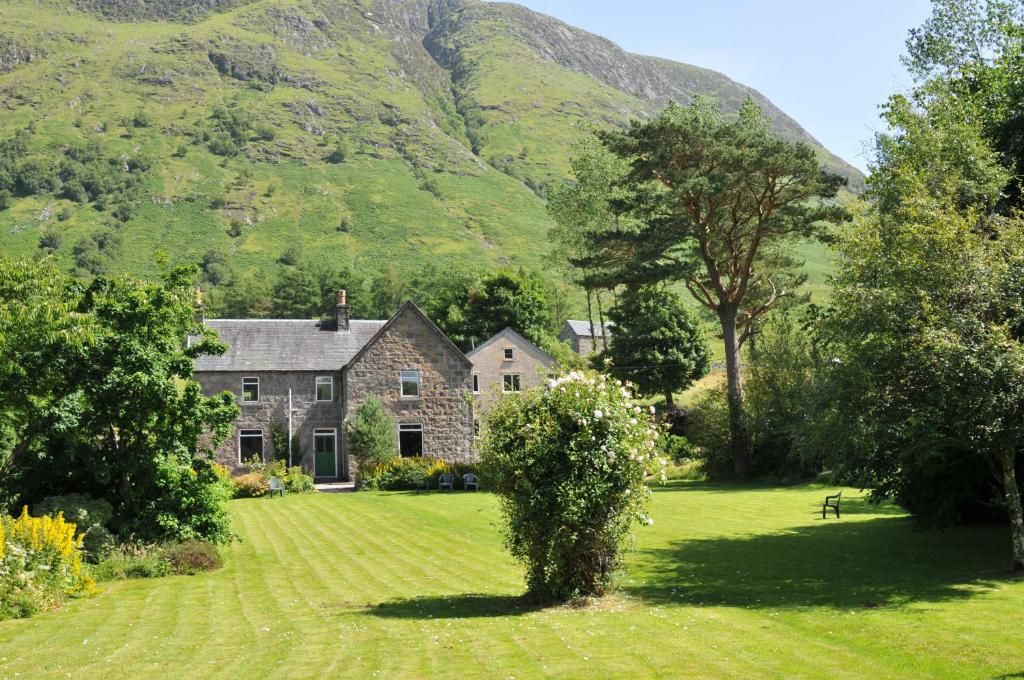 a house in the middle of a field with mountains in the background at Achintee Farm Guest House in Fort William