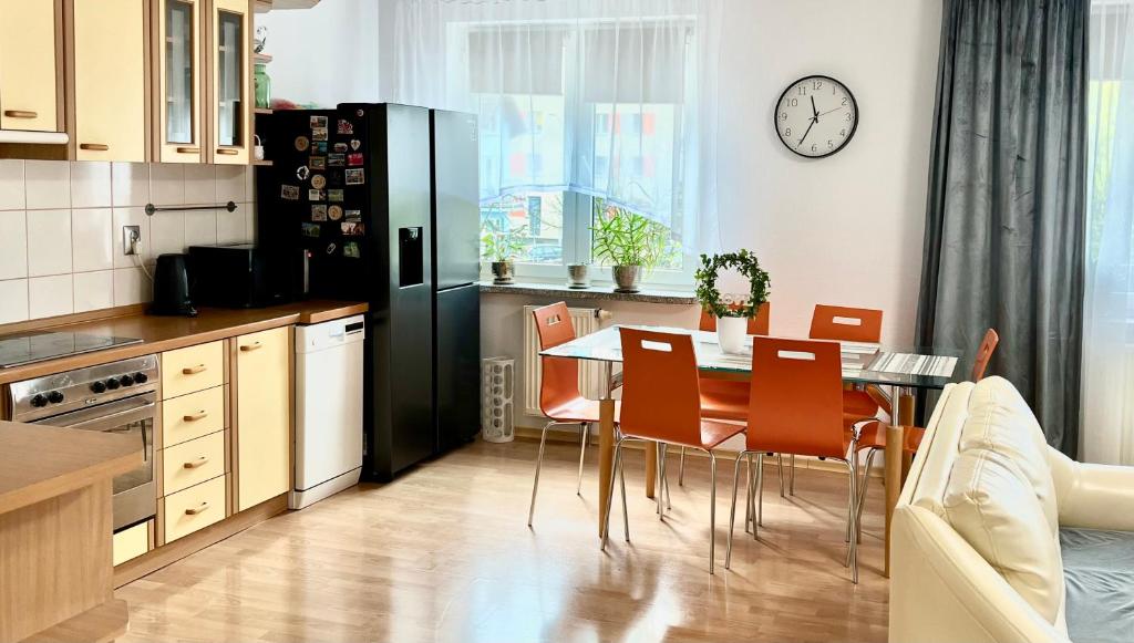 a kitchen with a dining table and a black refrigerator at Przytulny apartament in Augustów