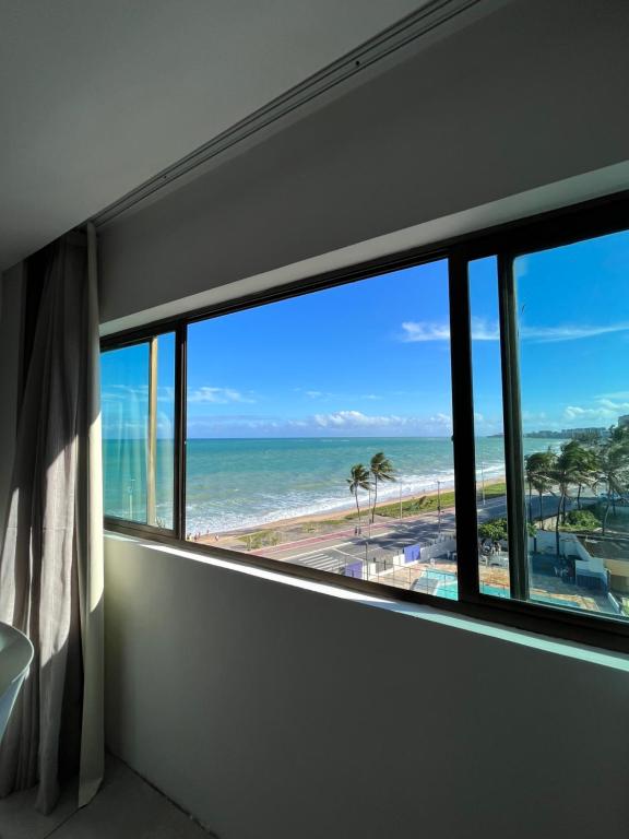 um quarto com uma janela com vista para a praia em Suíte 511, do Hotel Ritz Suítes em Maceió