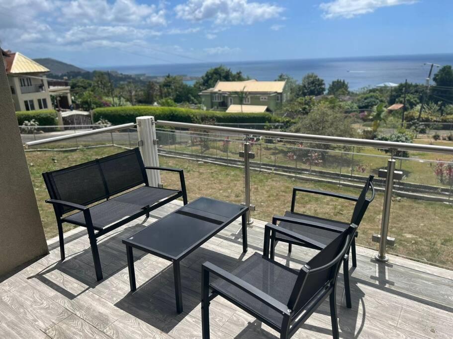 two black chairs and a table on a balcony at Château Charles, Coubaril, stunning Ocean view a 12 min drive to Vigie Beach in Castries