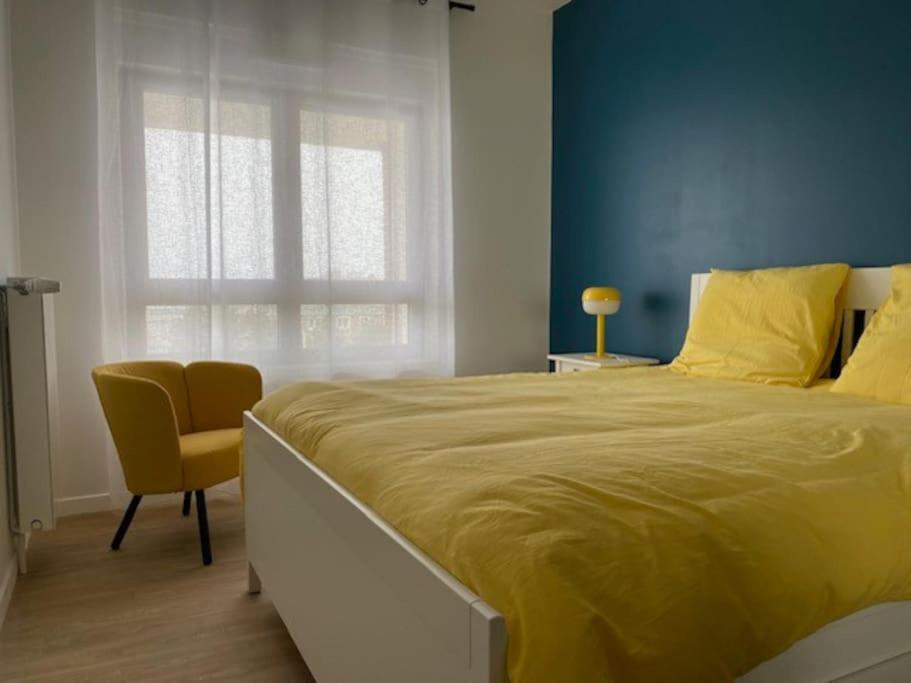 a bedroom with a large bed with a yellow blanket at Bel appartement avec vue sur la Baie d&#39;Authie in Berck-sur-Mer