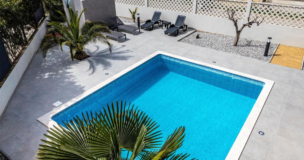 a blue swimming pool on a patio with a palm tree at Villa Patricija in Medulin