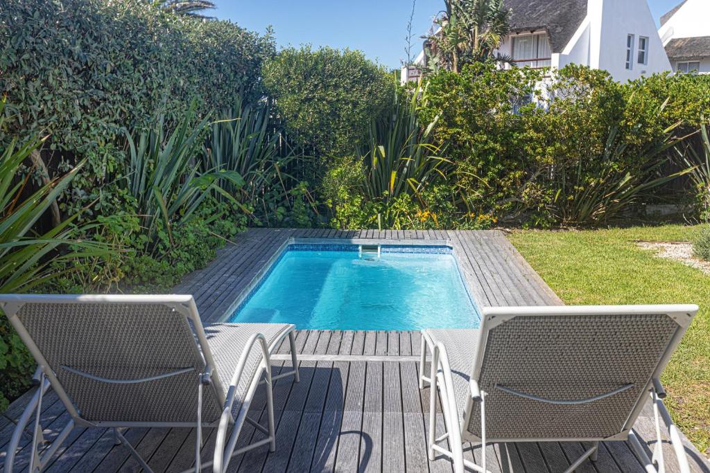 una piscina con 2 sillas, una mesa y una piscina en A Resort Gem With A Pool en Cape St Francis
