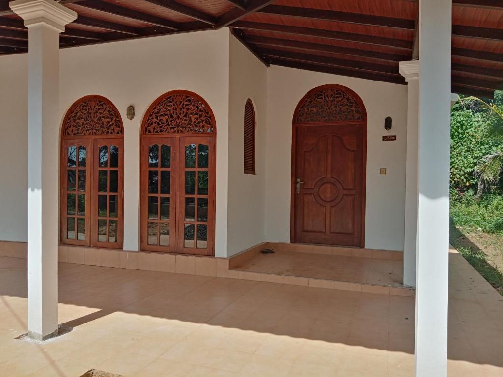 uma casa com uma porta de madeira e três janelas em Challsvilla Holiday Family Rooms Matara em Kekanadura