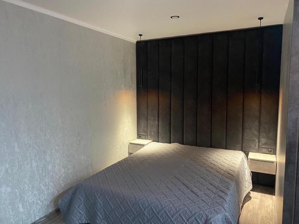 1 dormitorio con 1 cama y un gran cabecero de madera en Апартаменты, en Semey