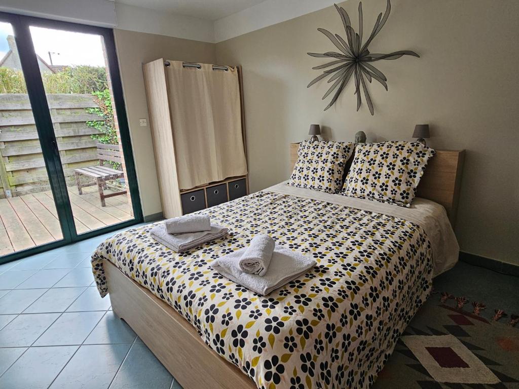 ein Schlafzimmer mit einem Bett mit Handtüchern und einer Uhr an der Wand in der Unterkunft L'Orée du Bois in Coutiches