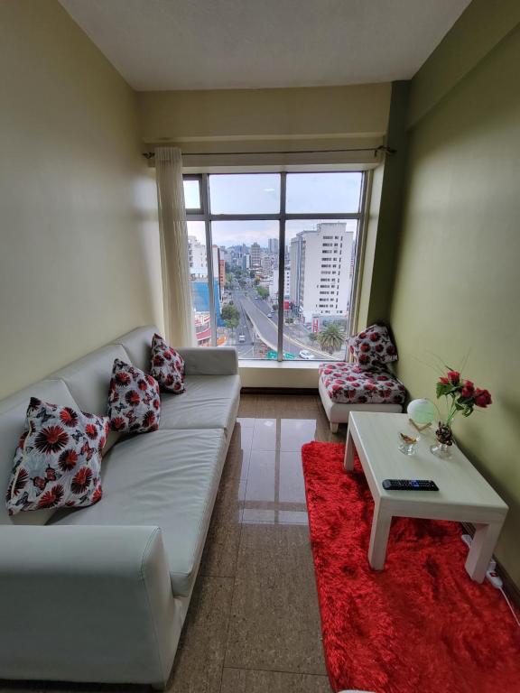 基多的住宿－SUITE, vista hermosa de Quito，带沙发、桌子和窗户的客厅