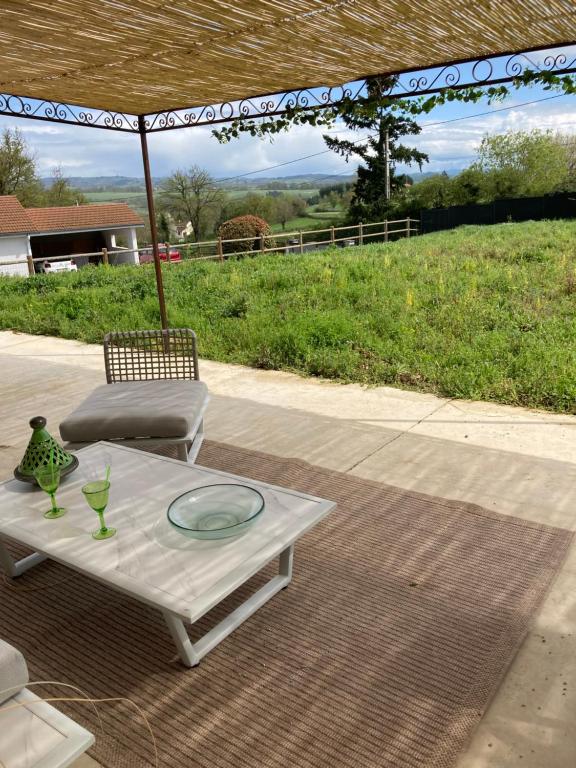 a white table and a chair and an umbrella at Maison proche de la Loire in Saint-Georges-de-Baroille