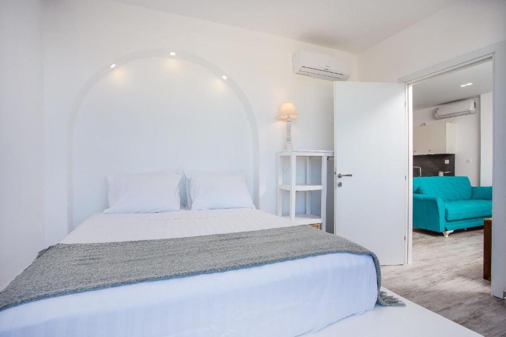 Ammos Apartment - in neu gebautem Designerhaus في فاليراكي: غرفة نوم بيضاء بسرير واريكة زرقاء