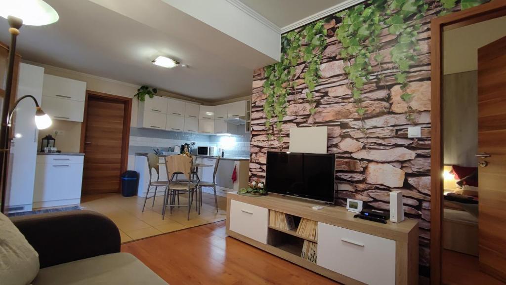 a living room with a tv and a stone wall at Limonádé Apartman in Gárdony