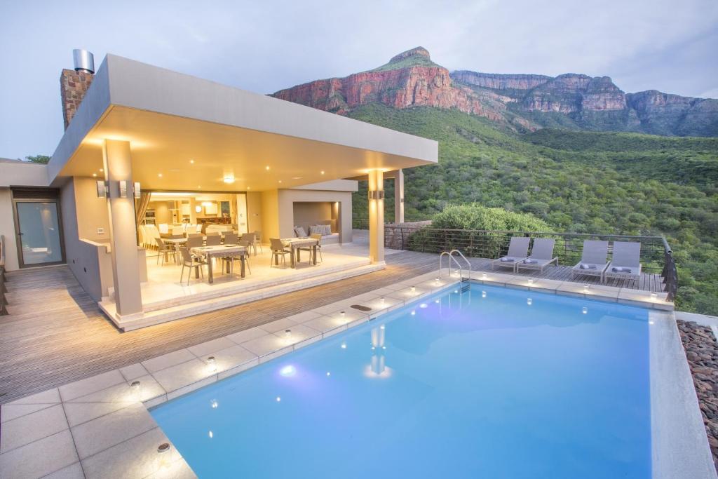 a house with a swimming pool in front of a mountain at umVangati House in Hoedspruit