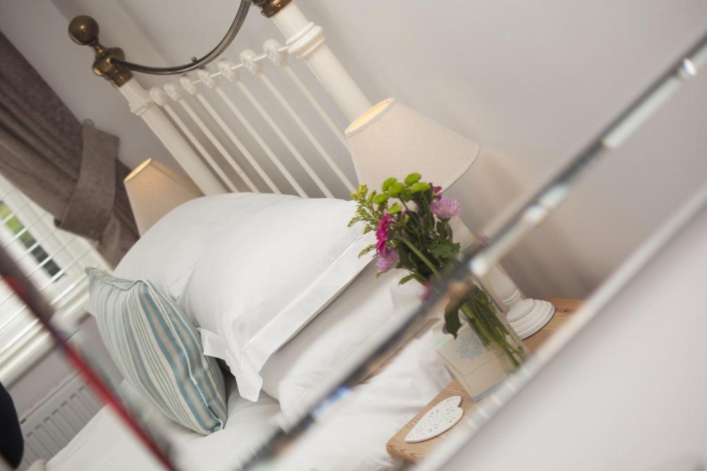 a bed with a pillow and flowers on a table at Trevose House in Padstow