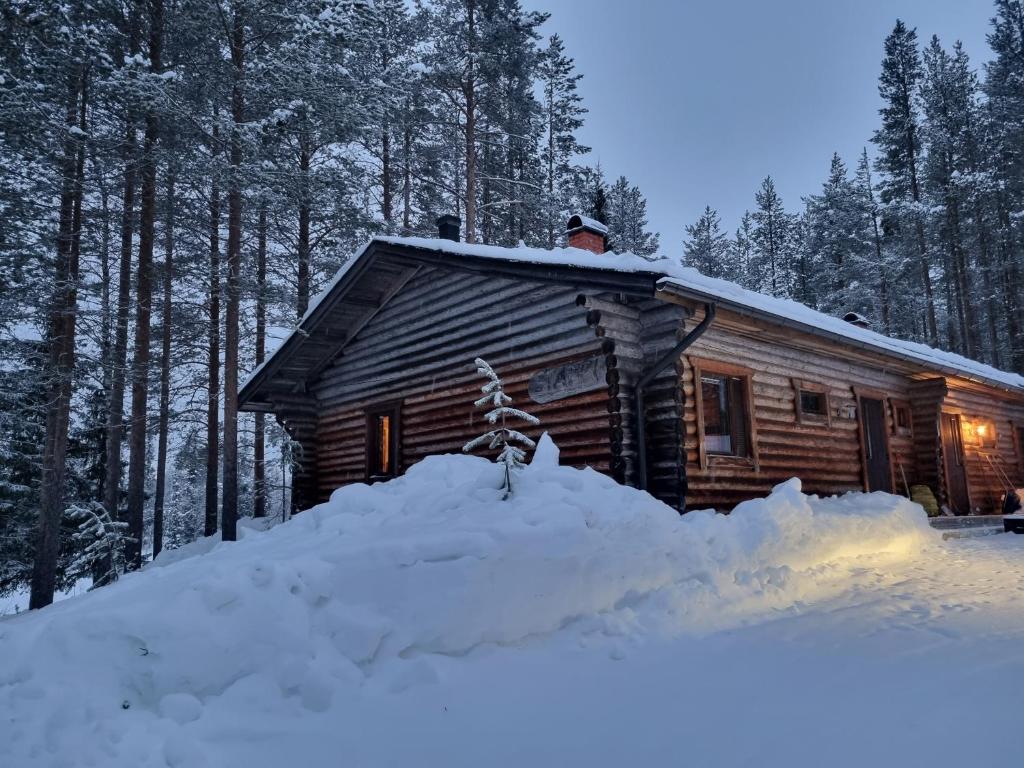 uma cabana de madeira com um monte de neve à sua frente em Ylläs Valokki em Ylläsjärvi