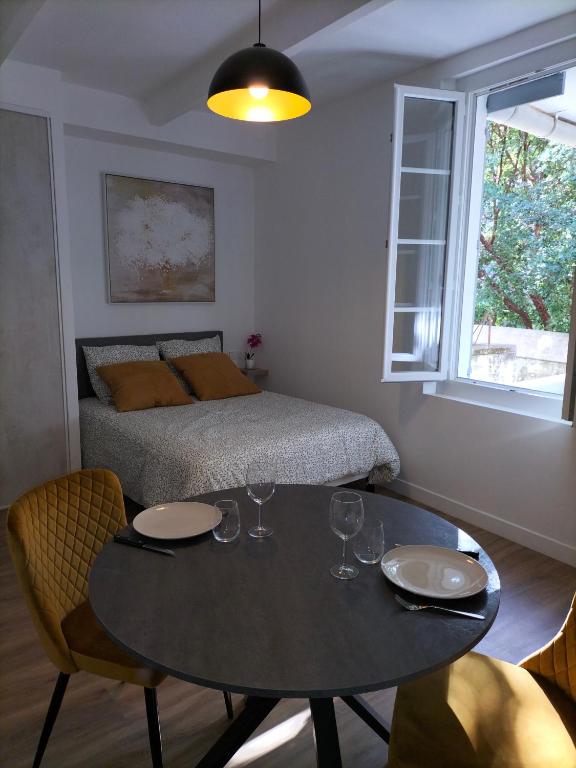a bedroom with a table and a bed and a table and chairs at Studio climatisé intra muros balcon in Avignon