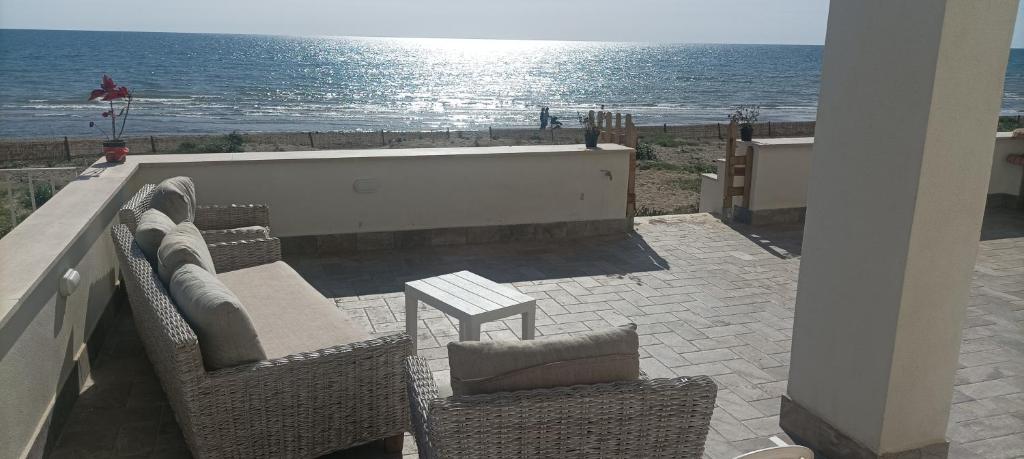 eine Terrasse mit Stühlen, einem Tisch und Meerblick in der Unterkunft the suite on the beach in Torvaianica