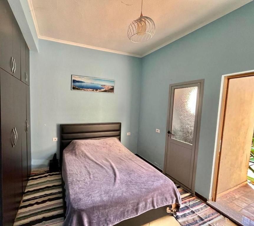 RENT ROOM -RENI - في Librazhd: غرفة نوم بسرير وبطانية ارجوانية