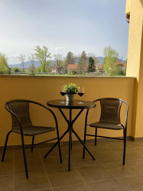 dos sillas y una mesa con dos copas de vino en Apartman Leo, en Klinča Sela