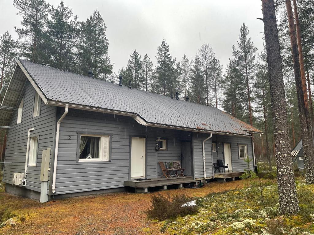 ein graues Haus mit einer Veranda im Wald in der Unterkunft Mökki Jyrkinkuja in Loimaa