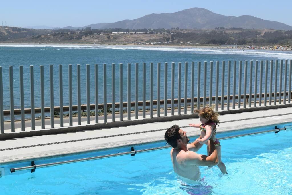 un uomo e un bambino in piscina di Pura Vida - apartamento con salida a la costa a Concón