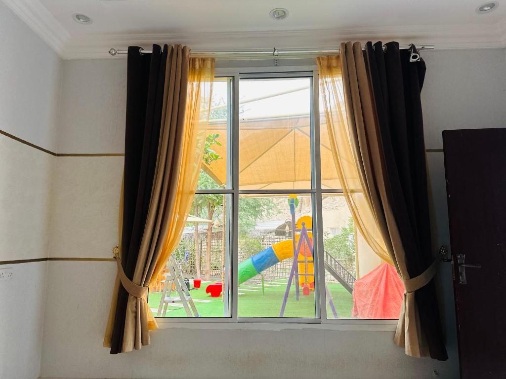 a window with a view of a playground at FIG SHADES مزرعة ظلال التين in Ţīwī