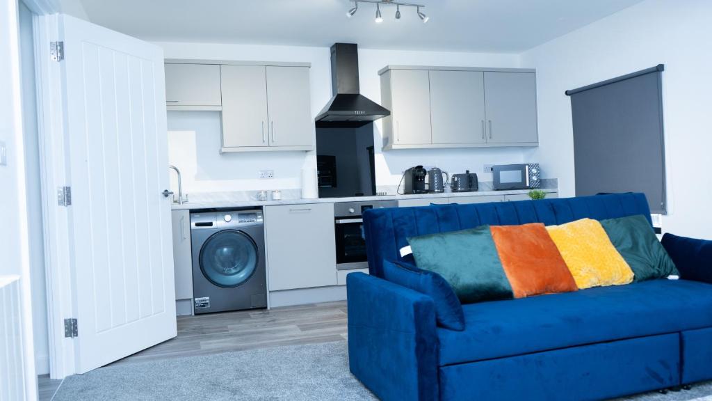 a living room with a blue couch and a kitchen at 1BR Sleeps 4, 3 mins from City centre & Local Gems in Burton upon Trent