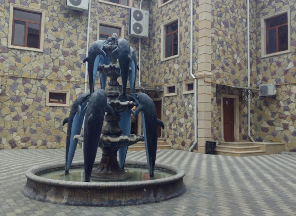 a statue of dolphins in a fountain in front of a building at Star Hotel in Shamakhi