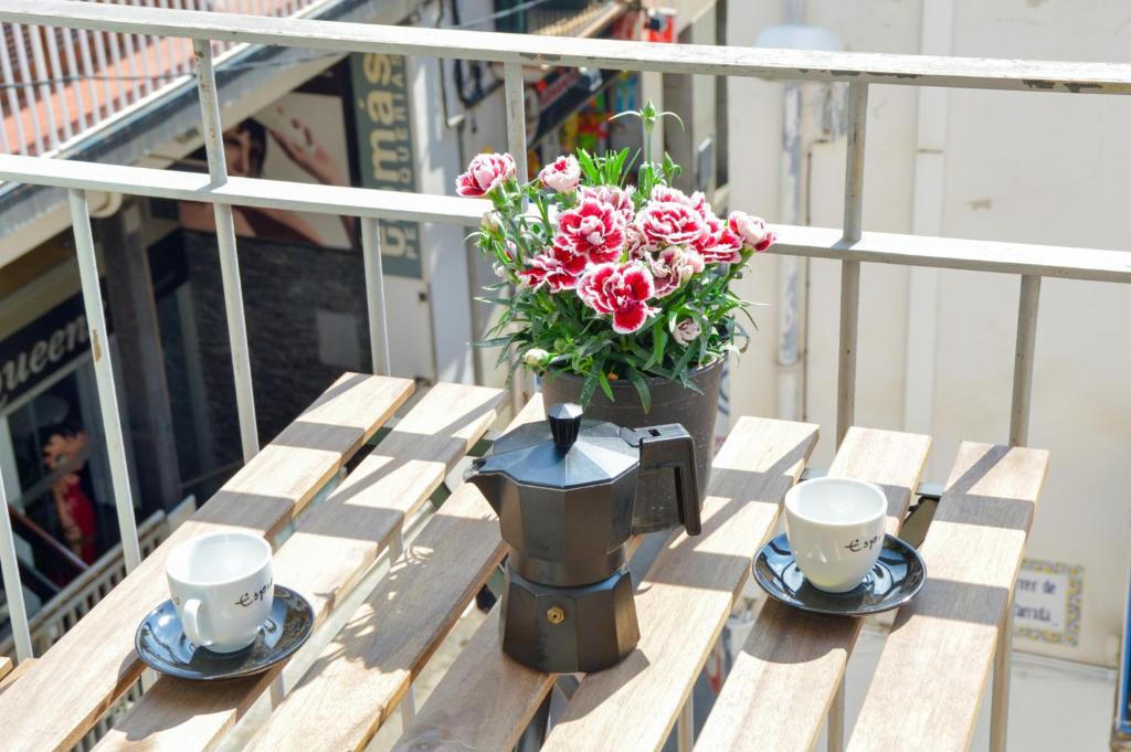 um vaso com flores em uma mesa com duas xícaras em Nova Apartment by Hello Homes Sitges em Sitges