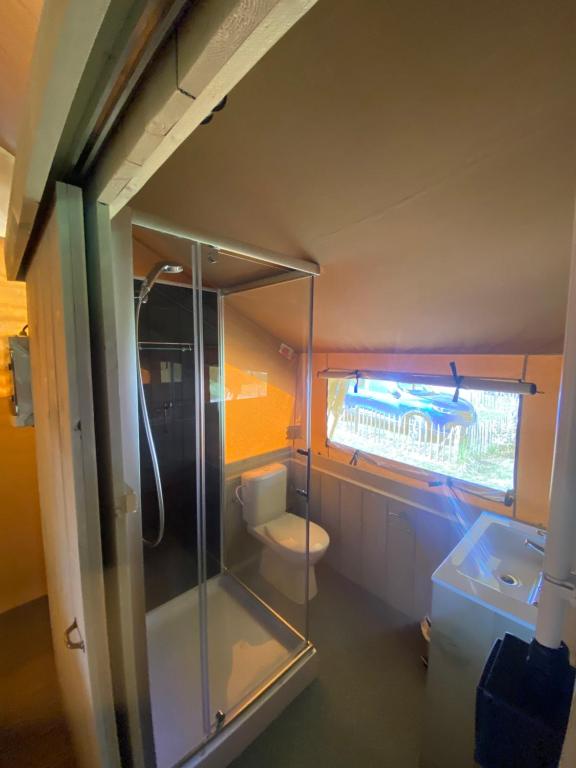 La salle de bains est pourvue d'une douche en verre et de toilettes. dans l'établissement Camping Dun-le-Palestel, à Dun-le-Palestel