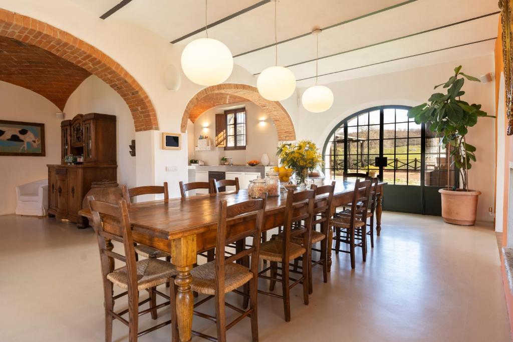 une grande salle à manger avec une table et des chaises en bois dans l'établissement LA FORNACE, à Asciano