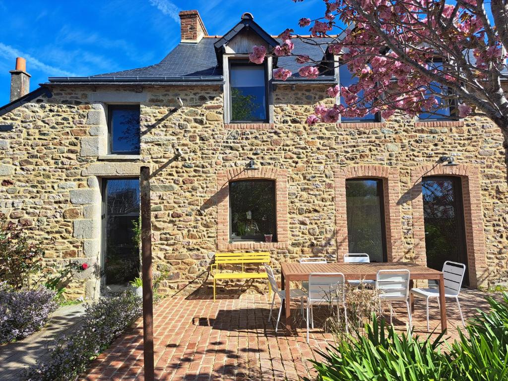 a stone house with a table and chairs in front of it at 600m bord de mer centre du val andre la maison des prés in Pléneuf-Val-André