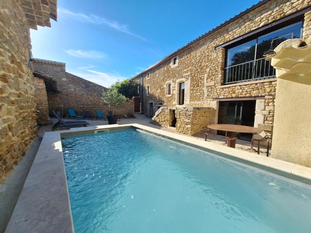 a swimming pool in front of a brick building at Chez Véro chambres d'hôtes & Maison en pierre contemporaine in Suze-la-Rousse