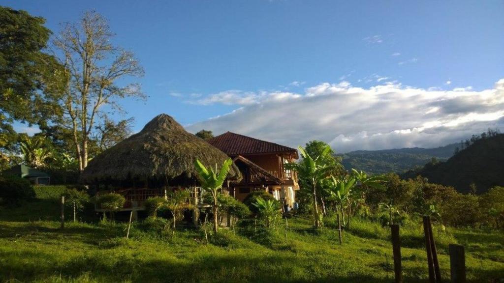 una casa con techo de paja en un campo en Finca Agroturística El Portal en Gachetá