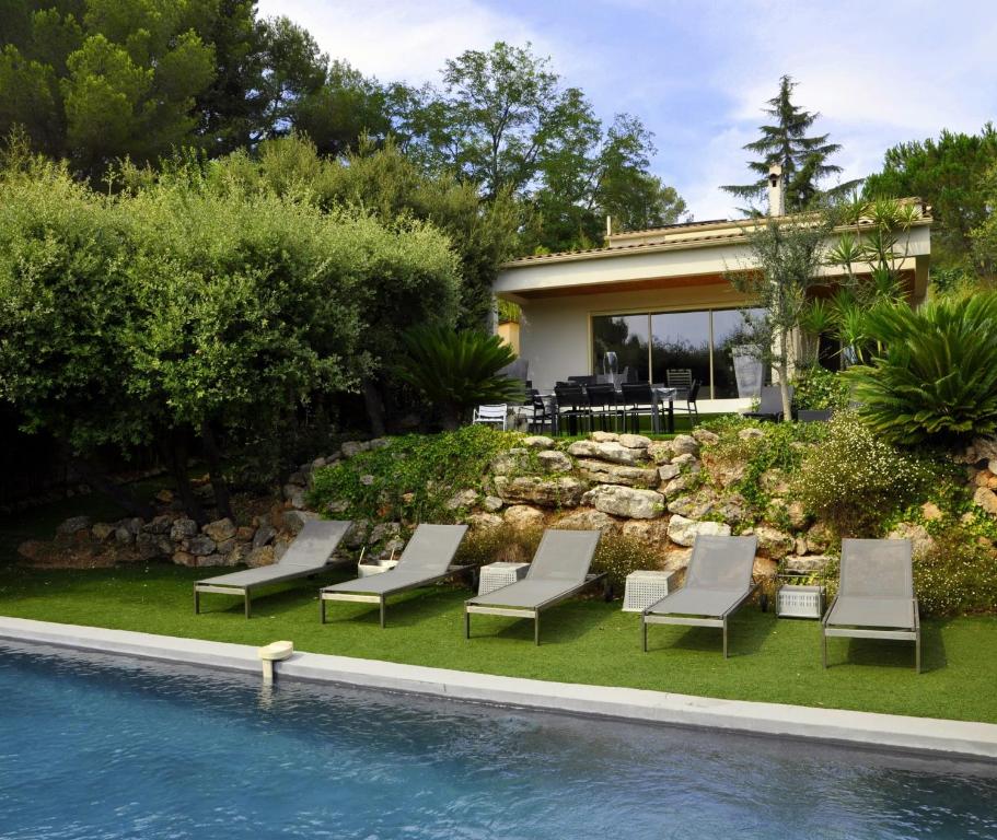un patio trasero con piscina y sillas y una casa en Villa de standing chambres climatisées avec piscine et jardin privatifs, en Biot